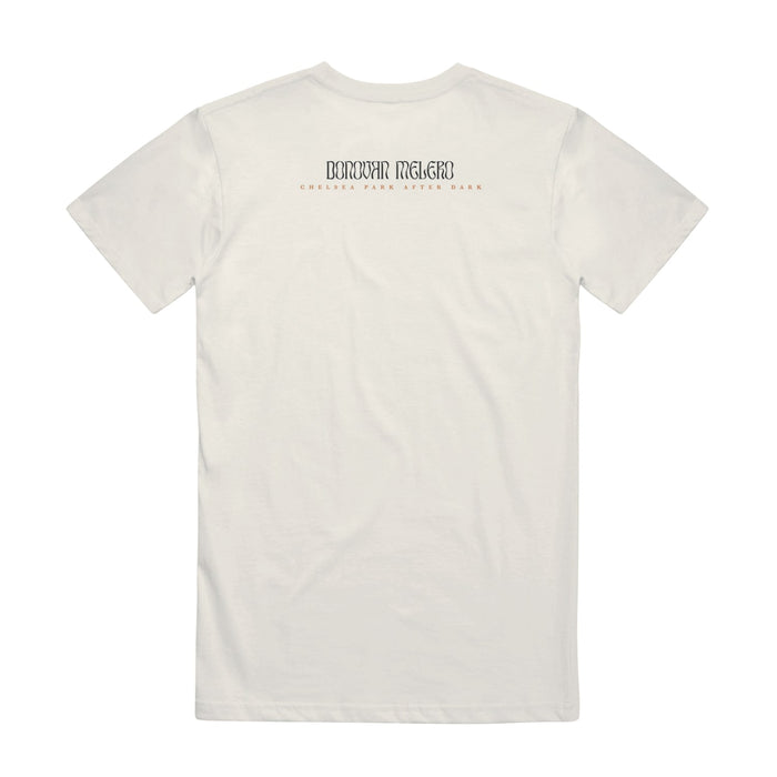 Back of a white short sleeve shirt, there is black text that says "DONOVAN MELERO". Below that, there is smaller red text that says "CHELSEA PARK AFTER DARK".