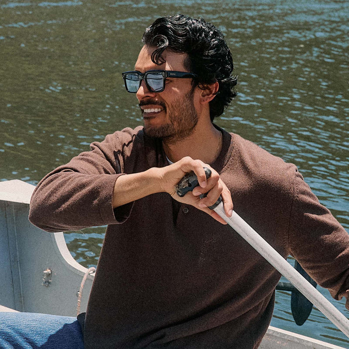 lifestyle - male on a boat wearing diff eyewear cash sunglasses with a black acetate frame and light blue tint lenses angled view