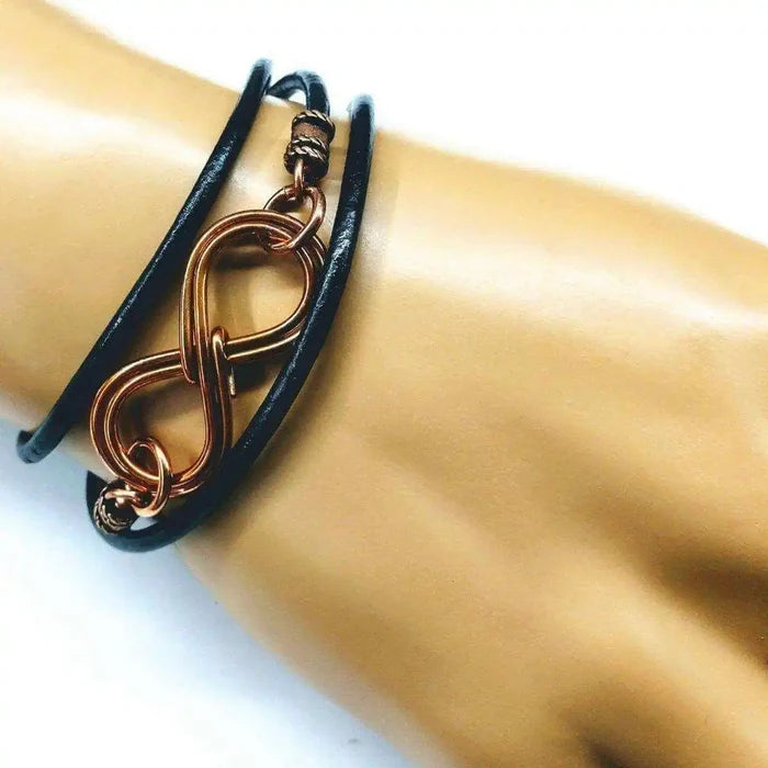 Copper Double Infinity Gender Neutral Leather Wrap Bracelet on a hand, showcasing its elegant design and infinity symbols.
