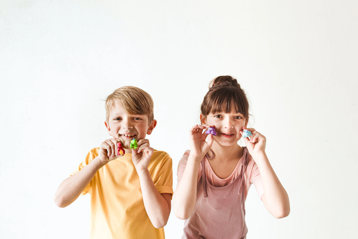 Boy and girl holding completed clay animals from OOLY Creatibles Mini Air Dry Clay Kits