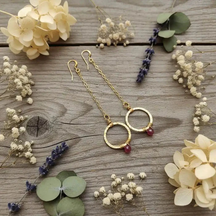 Gold Filled Wrapped Pink Chalcedony Open Circle Earrings surrounded by dried flowers and greenery.