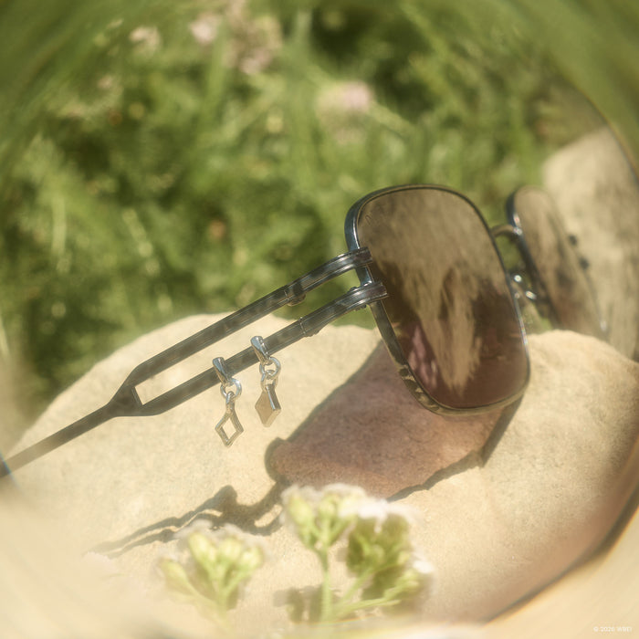 still life - diff eyewear x practical magic kylie rectangle sunglasses detailed view of temples laying on a rock outdoors