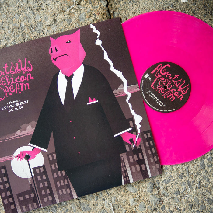 Vinyl jacket with a drawing of a pig ina suit standing in front of a city with the moon behind buildings. In the top left there is text in pink that says GATSBY'S AMERICAN DREAM. Peeking out of the jacket is a pink vinyl. Both are laying on an asphalt surface.