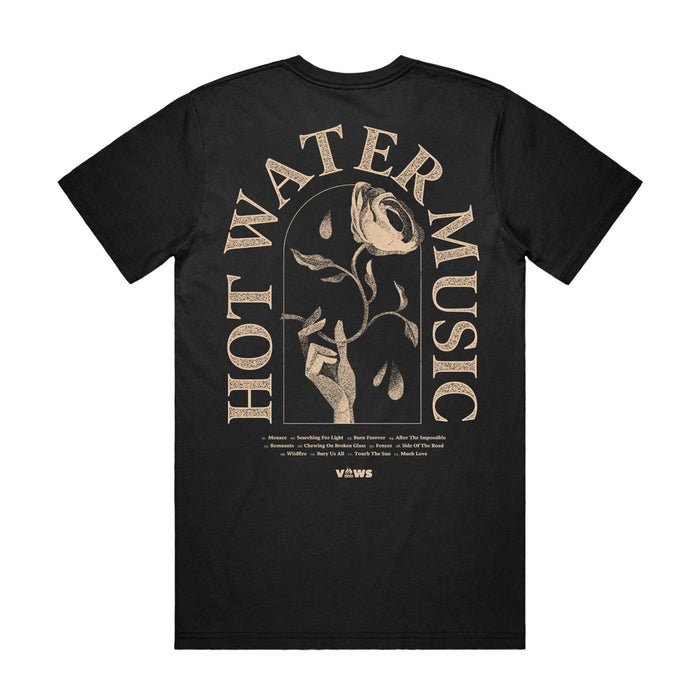 Photo of the back of the shirt. The back of the shirt has the band name "HOT WATER MUSIC" arched around a hand holding a rose. There is also very small text underneath the main design that is unreadable in the photo.