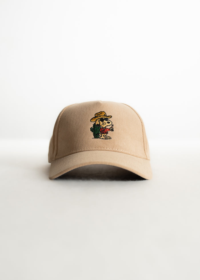 Tan baseball cap with a colorful embroidered cartoon character on the front, set against a plain white background.