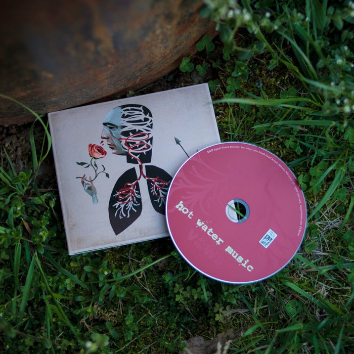 A Hot Water Music VOWS CD with a pink disc rests on grass beside its cover, displaying abstract art of a figure with a rose and arteries. This presale item from Hot Water Music includes a full album digital download.