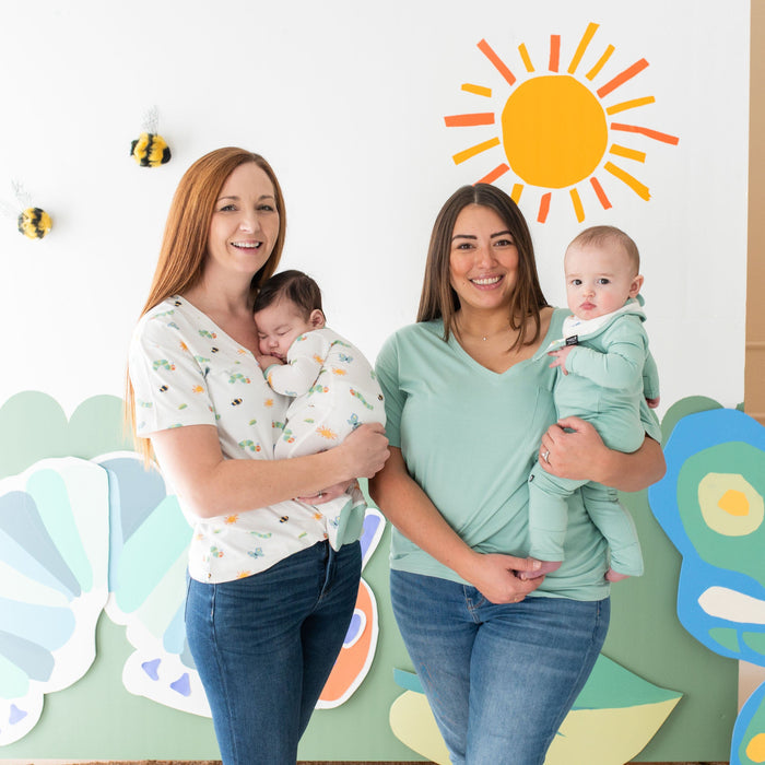 Women holding their infants in matching Kyte Baby outfits