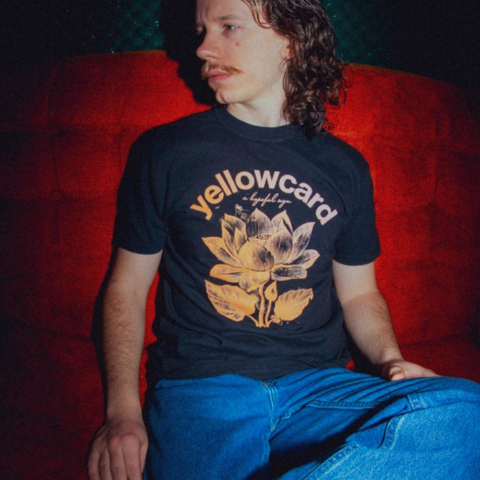 Photo of a man wearing the shirt. He is sitting on a red sofa.
