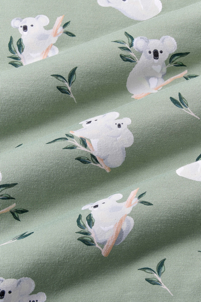 Close up of Bamboo Fabric: An all-over print featuring various grey koalas perched and hanging on eucalyptus branches, including one koala with her joey on her back, over a dusty sage green background color called Thyme.