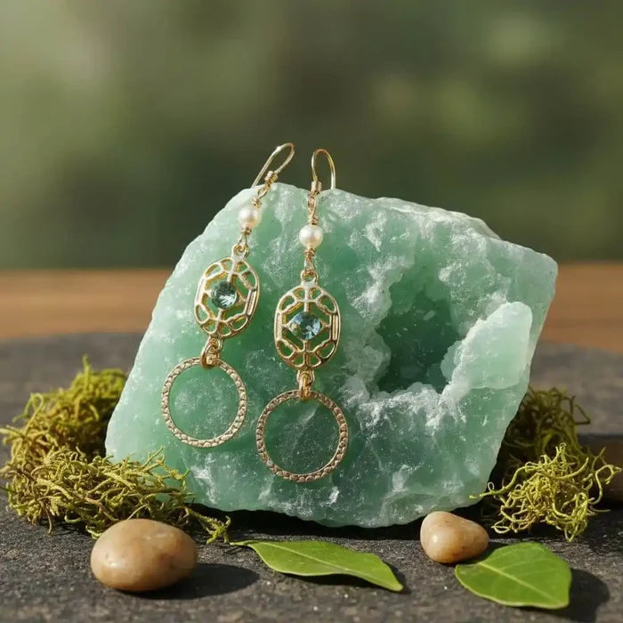 14 KT Gold Filled Green Crystal Circle Filigree Earrings displayed on a green crystal stone with natural elements.