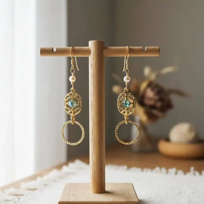 14 KT Gold Filled Green Crystal Circle Filigree Earrings displayed on a wooden stand with a soft background.