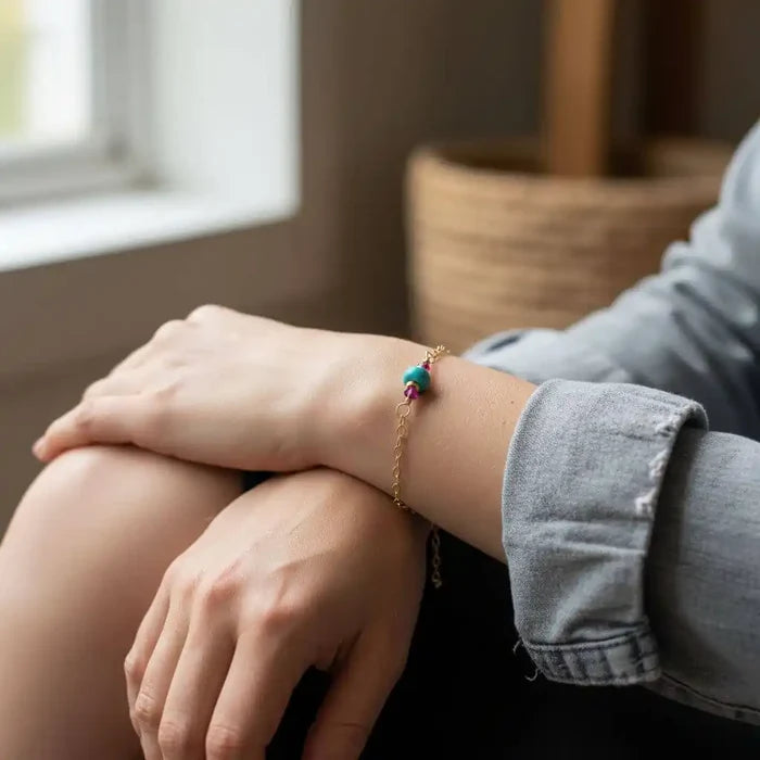 Model wearing a 14K Gold Filled Pink and Turquoise Gemstone Dainty Bracelet on her wrist near a window.