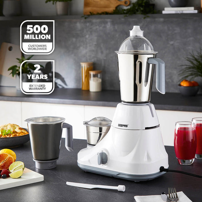 A lifestyle image of the 3-in-1 mixer grinder on top of a kitchen countertop with glasses of juice, dry grinded spices next to it.