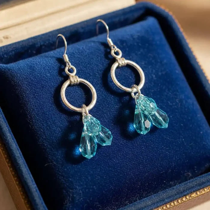925 Silver Hammered Aqua Crystal Cascading Drop Earrings displayed in a blue jewelry box.