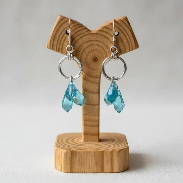 925 Silver Hammered Aqua Crystal Cascading Drop Earrings displayed on a wooden stand, showcasing aqua Swarovski crystals.