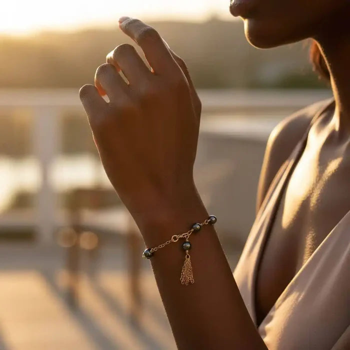Adjustable 14 KT Gold Filled Hematite Chain Tassel Bracelet worn by a woman in a sunlit setting.