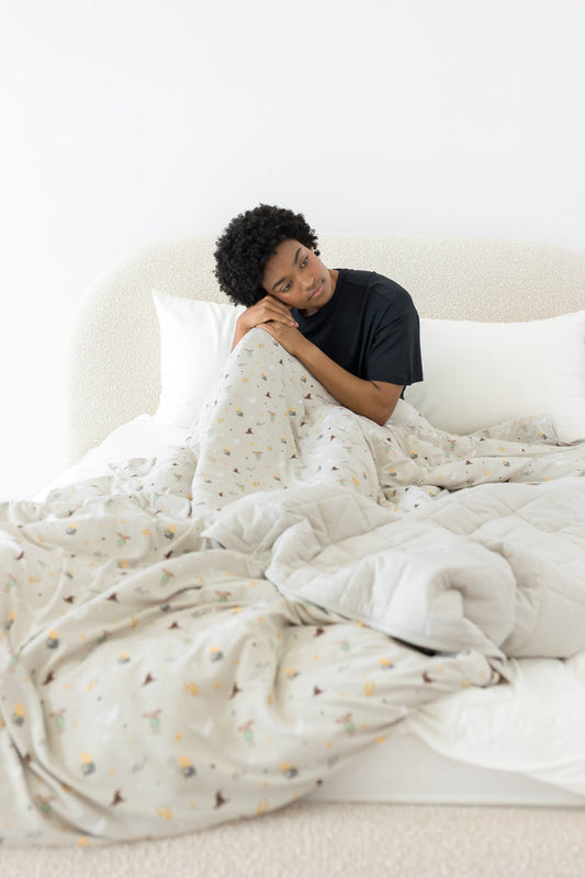 Person lying in bed under a soft, Harry Potter patterned adult blanket in a minimalistic room.