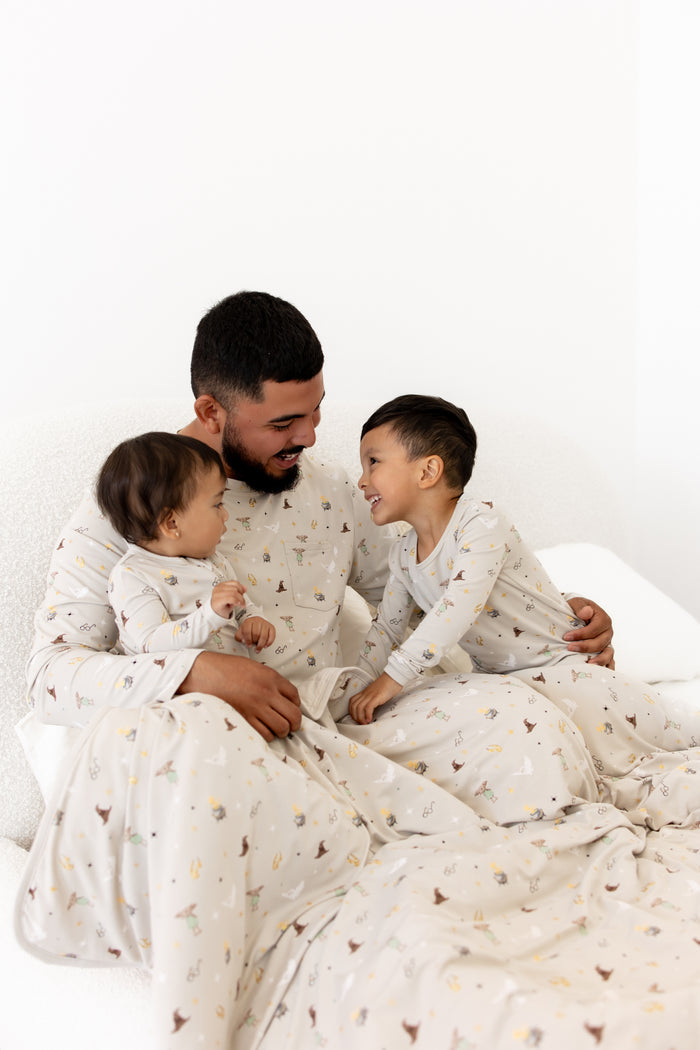 Man and two children in matching pajamas sitting on a bed with Harry Potter blanket