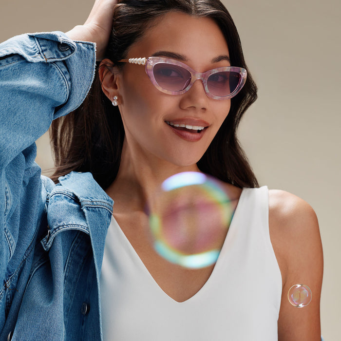 lifestyle - female wearing diff eyewear x disney princess featuring the ariel 3.0 cateye sunglasses with a pink acetate frame and wine gradient lenses front view