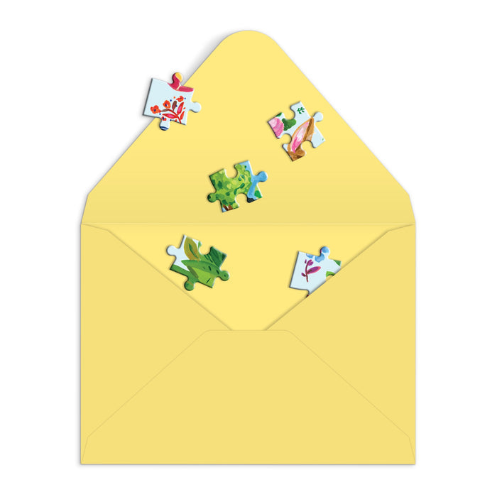 The Artisanal Eggs Greeting Card Puzzle by Jennifer O Lewis /August Wren features colorful, patterned jigsaw pieces in a yellow envelope—perfect for sending unique Easter wishes.