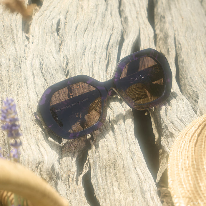 still life - diff eyewear x practical magic 2 aunt jet round sunglasses laying on a piece of drift wood