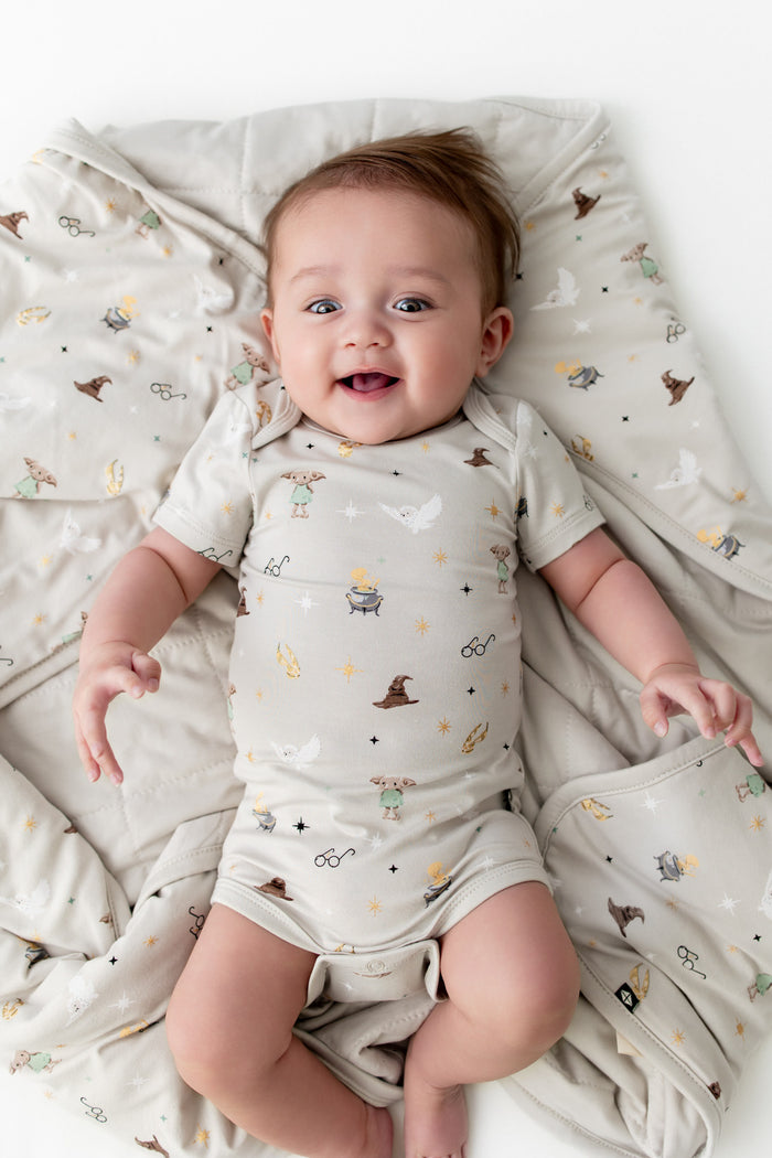 Baby wrapped in a beige blanket with Harry Potter prints, wearing a similar print bodysuit.