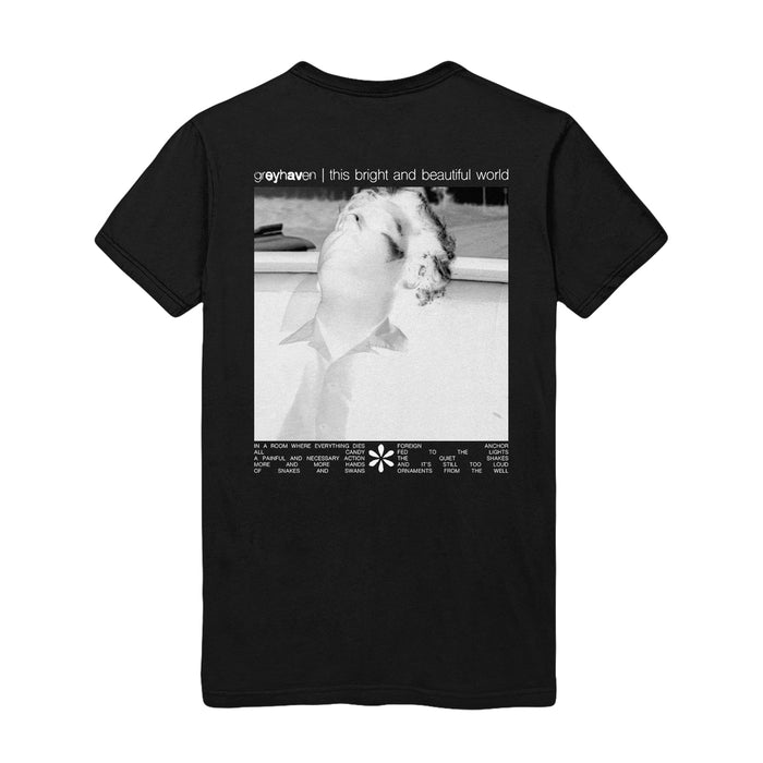 Back of black short sleeve shirt with an x-ray style of someone looking upwards. In the top left, there is small white text that says "greyhaven". In the middle bottom, there is a small white flower design, the same as on the front.