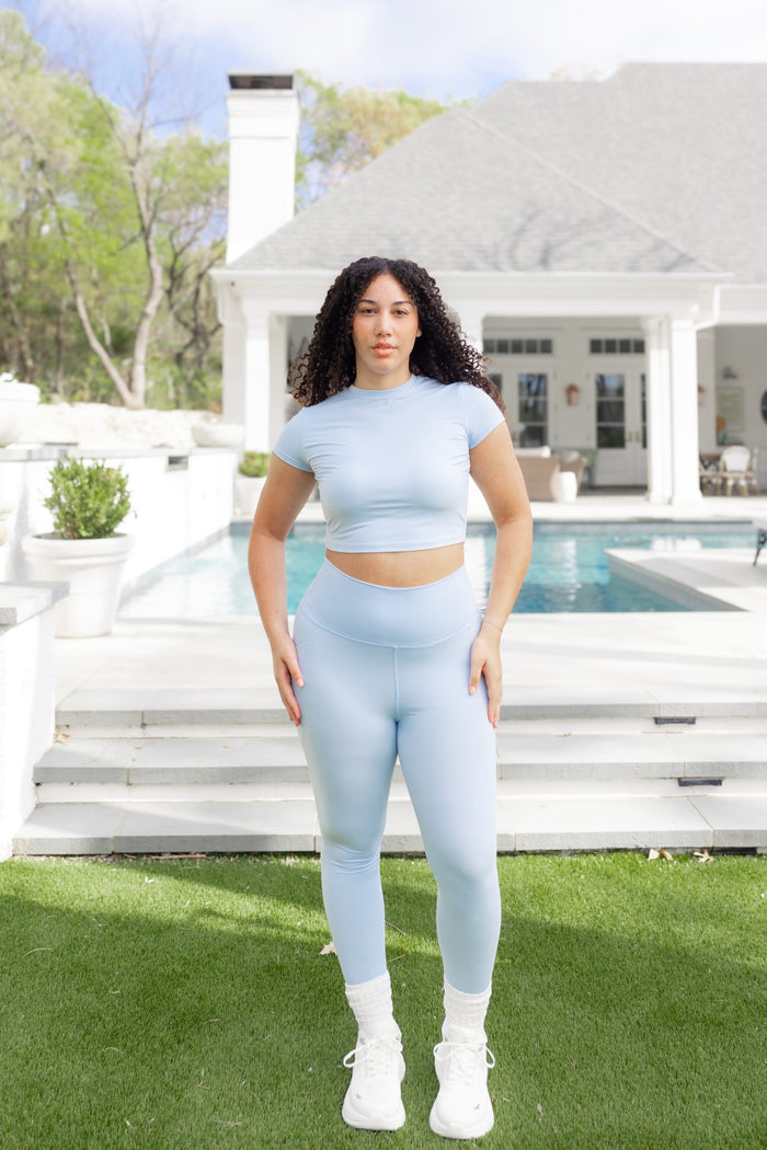 Female posing in front of a pool wearing the Bamboo Flex Baby Tee in Breeze with matching bamboo flex leggings
