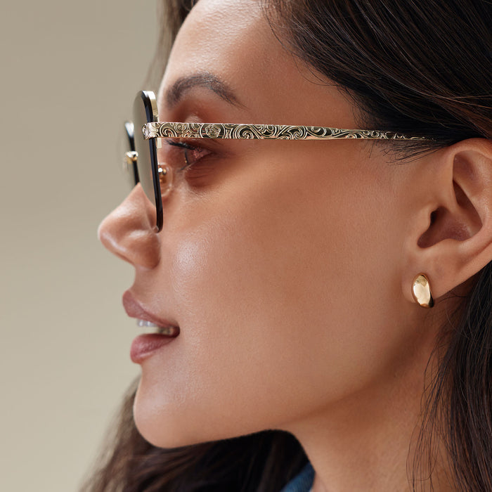 lifestyle - female wearing diff eyewear x disney princess featuring the belle 3.0 cateye sunglasses with a metal gold frame and brown gradient lenses detailed temple view