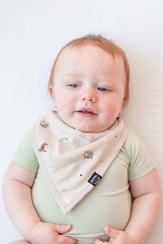 Baby wearing a bib with Harry Potter prints on a beige background.