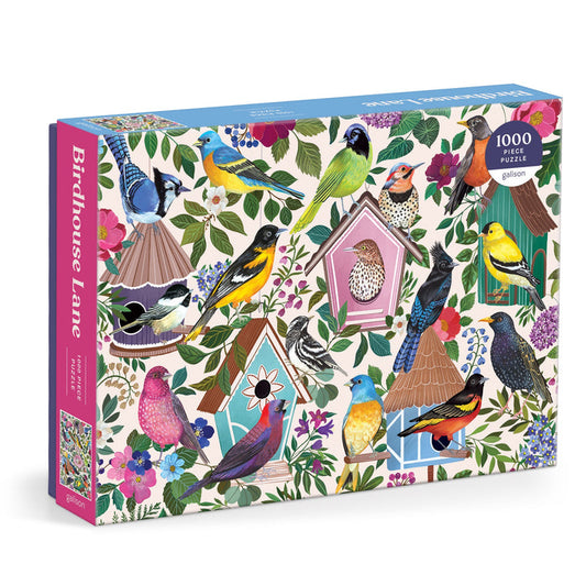 The Birdhouse Lane 1000 Piece Puzzle by Christine De Carvalho showcases colorful birds and decorative birdhouses with flowers on a cream background. The box features pink and blue sides.