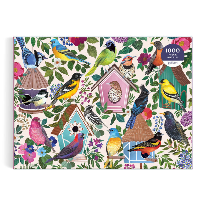 Enjoy assembling the Birdhouse Lane 1000 Piece Puzzle by Christine De Carvalho, featuring vibrant birds on and around decorative birdhouses surrounded by colorful flowers and lush greenery—a delightful celebration of avian beauty.