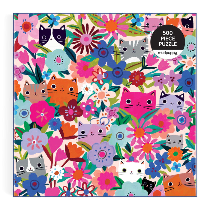 The Blooming Cats 500 Piece Puzzle by Tara Lilly features illustrated cats in various colors peeking out from vibrant pink, purple, blue, orange, and red flowers. The Tara Lilly brand name appears on the colorful box.