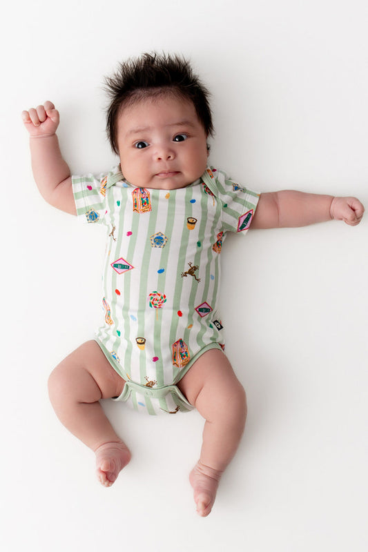 Baby wearing a green and white striped bodysuit with colorful Harry Potter patterns on a white background