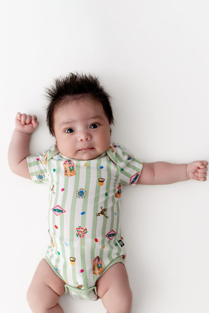 Baby wearing a green and white striped bodysuit with colorful Harry Potter patterns on a white background