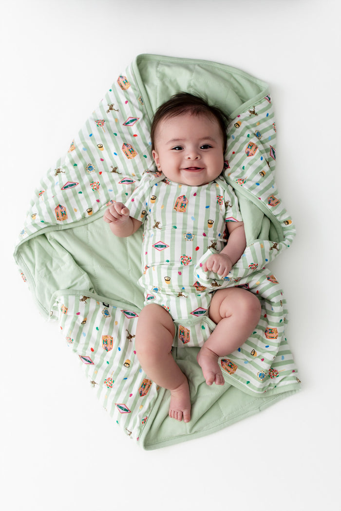 Baby wrapped in a green and white striped Baby blanket with colorful Harry Potter patterns, wearing a similar print bodysuit on a white background