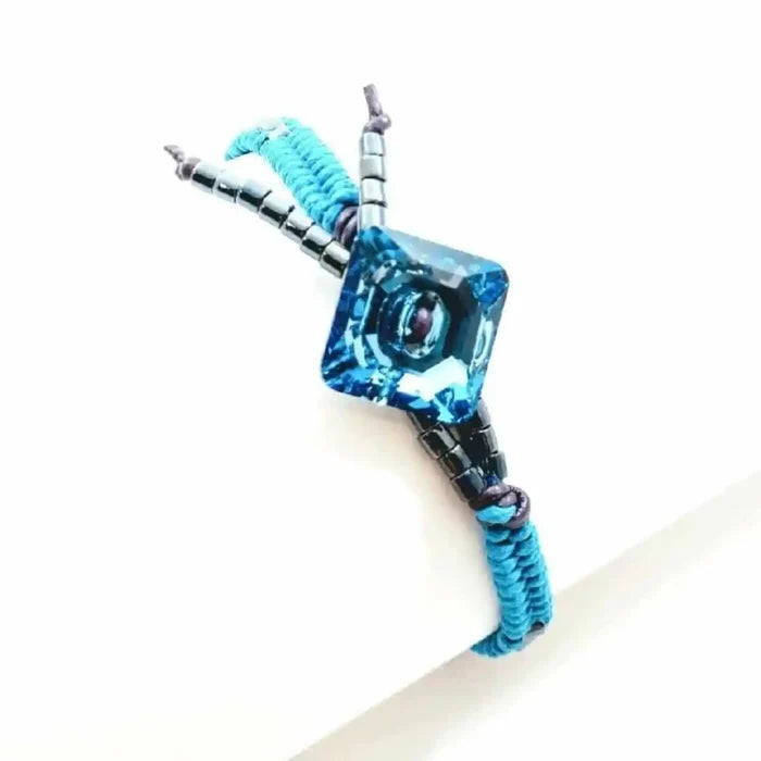 Aqua Hematite Bead Braided Swarovski Crystal Button Bracelet displayed on a white background with a blue crystal centerpiece.