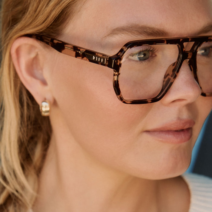lifestyle - female in a library wearing diff eyewear cameron navigator prescription glasses with a espresso tortoise acetate frame detailed view