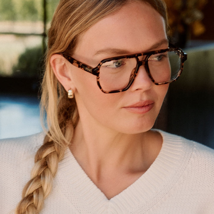 lifestyle - female in a library wearing diff eyewear cameron navigator prescription glasses with a espresso tortoise acetate frame angled view
