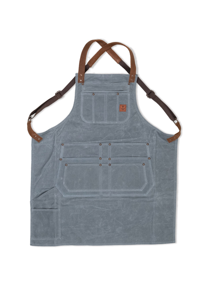 Gray canvas apron with brown leather straps, multiple pockets, and an anchor logo. Ideal for cooking or crafting activities.