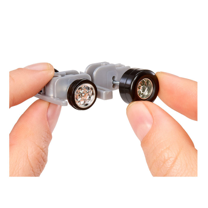 Small car body held between fingers with a white background