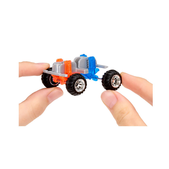 Close-up of hands holding a small truck bottom component with silver rims and black tires on a white background