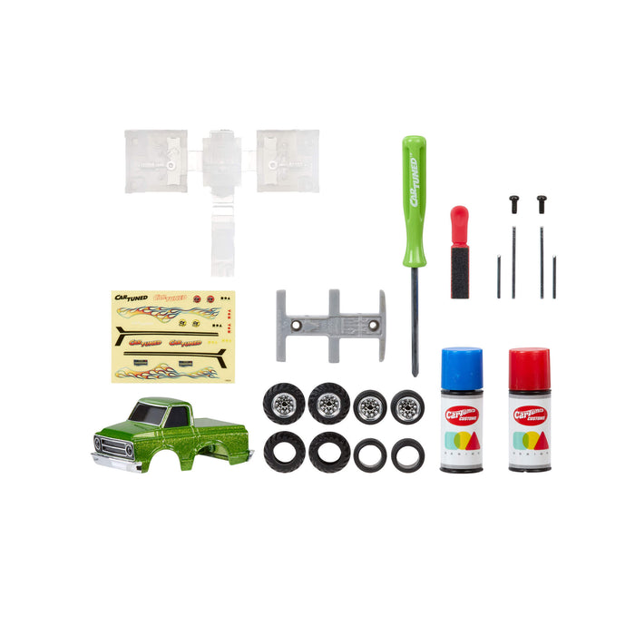 Collection of model truck accessories including a green base, wheels, tools, and paint cans on a white background