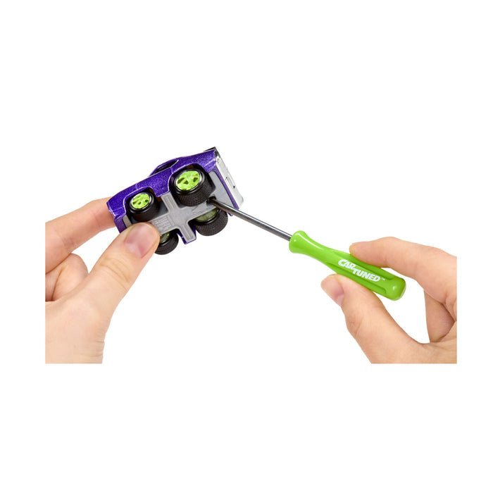 Person using a green screwdriver to connect the cars top and bottom on a white background
