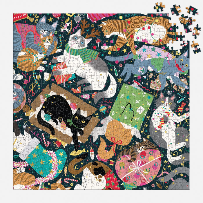 The Catmas Chaos 500 Piece Foil Puzzle by Maria Kee showcases playful cats in festive scenes with ornaments, yarn, gifts, and decorations. Just a few pieces remain to finish the holiday cat puzzle’s top right corner.