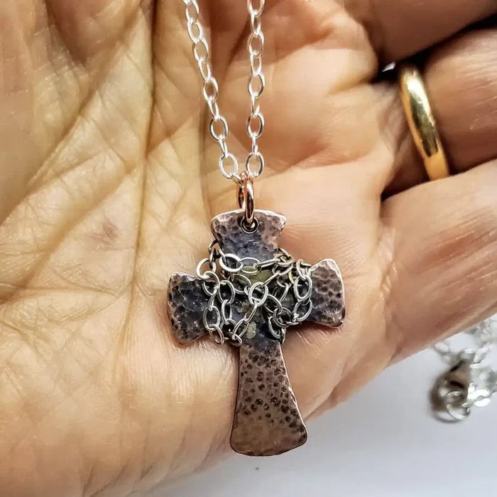Chained Hammered Copper Cross Necklace For Him Or Her held in a hand, showcasing its unique hammered texture and chain detail.