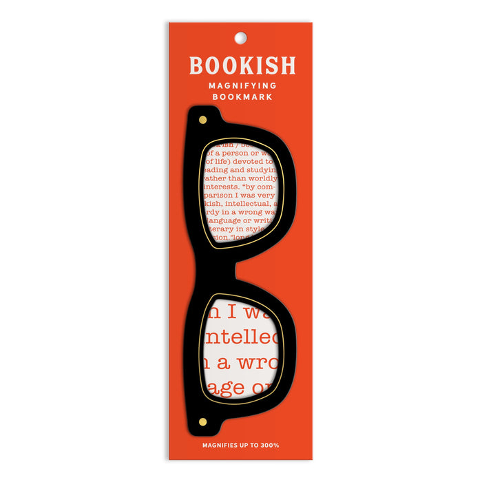 A stylish bookmark shaped like black eyeglasses, the Galison Classic Readers Bookmark with Magnifier, is displayed on a red card with magnified text visible through the lenses. Bottom text reads: MAGNIFIES UP TO 300%.