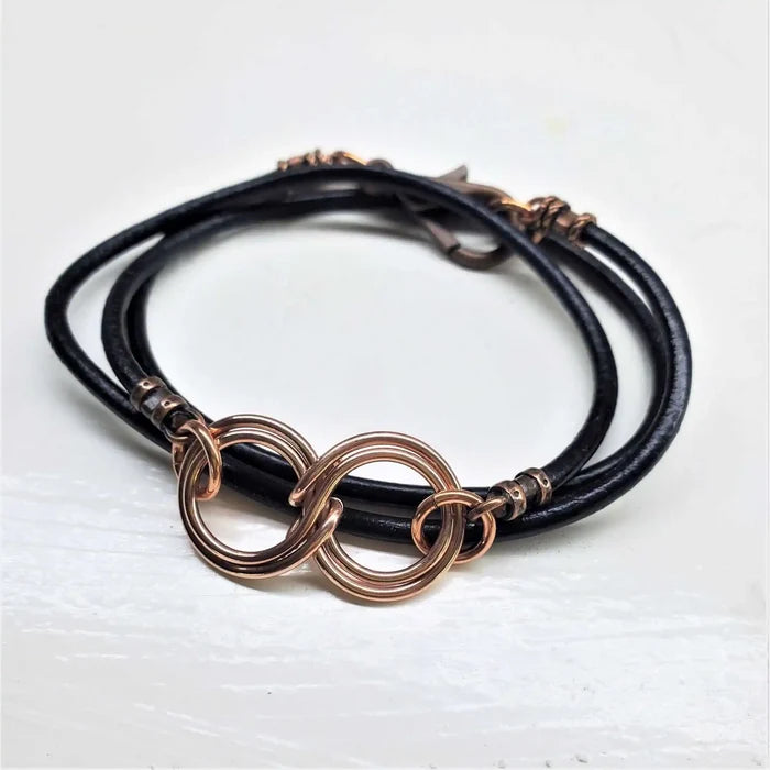 Copper Double Infinity Gender Neutral Leather Wrap Bracelet on black leather cord with intertwined copper symbols.