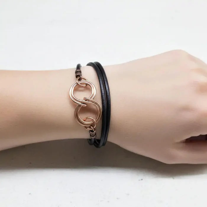 Copper Double Infinity Gender Neutral Leather Wrap Bracelet worn on wrist, showcasing interlocking infinity symbols on black leather.