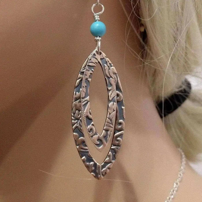 Copper Embossed Pointed Oval Turquoise Bead Earrings on display, showcasing intricate designs and vibrant turquoise bead.